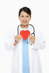 Cheerful medical personnel holding up a red heart